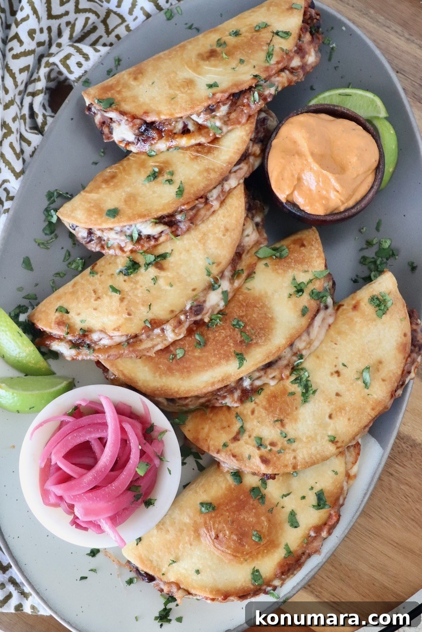 Smoky Black Bean Tacos with Avocado Lime Crema 6 tacos on a platter with a side bowl of pickled onions and a side bowl of chipotle sauce