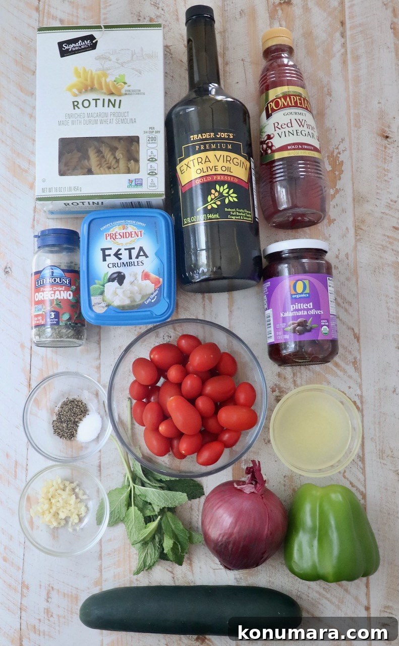 ingredients for Greek pasta salad on a white wood board