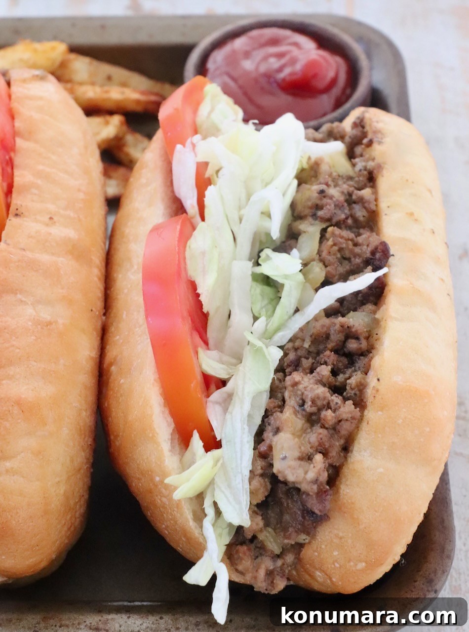 New York Bodega Chopped Cheese Sandwich Recipe 10 chopped cheese sandwich on a metal baking sheet with a small bowl of ketchup behind the sandwich