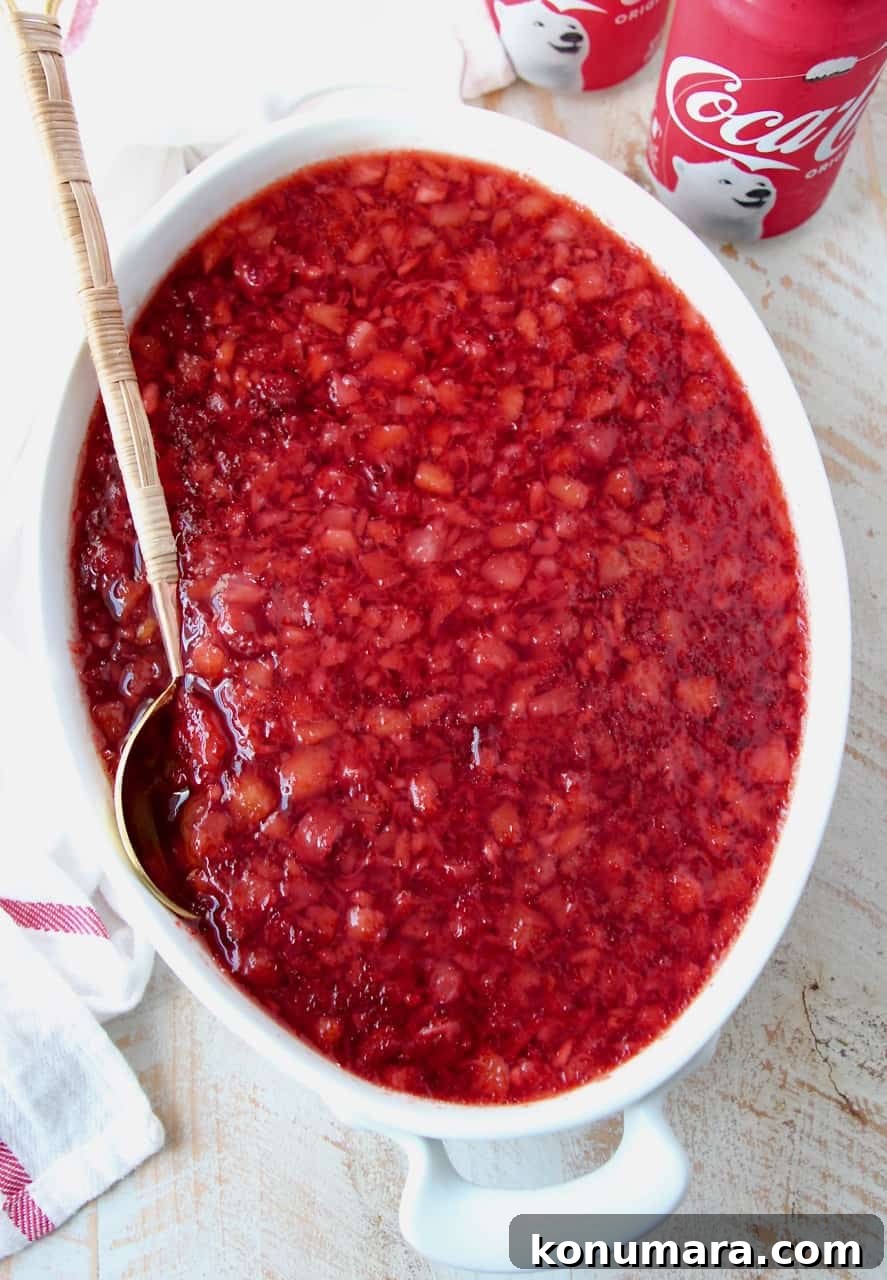 overhead image of cherry coke jello salad in white serving dish with spoon
