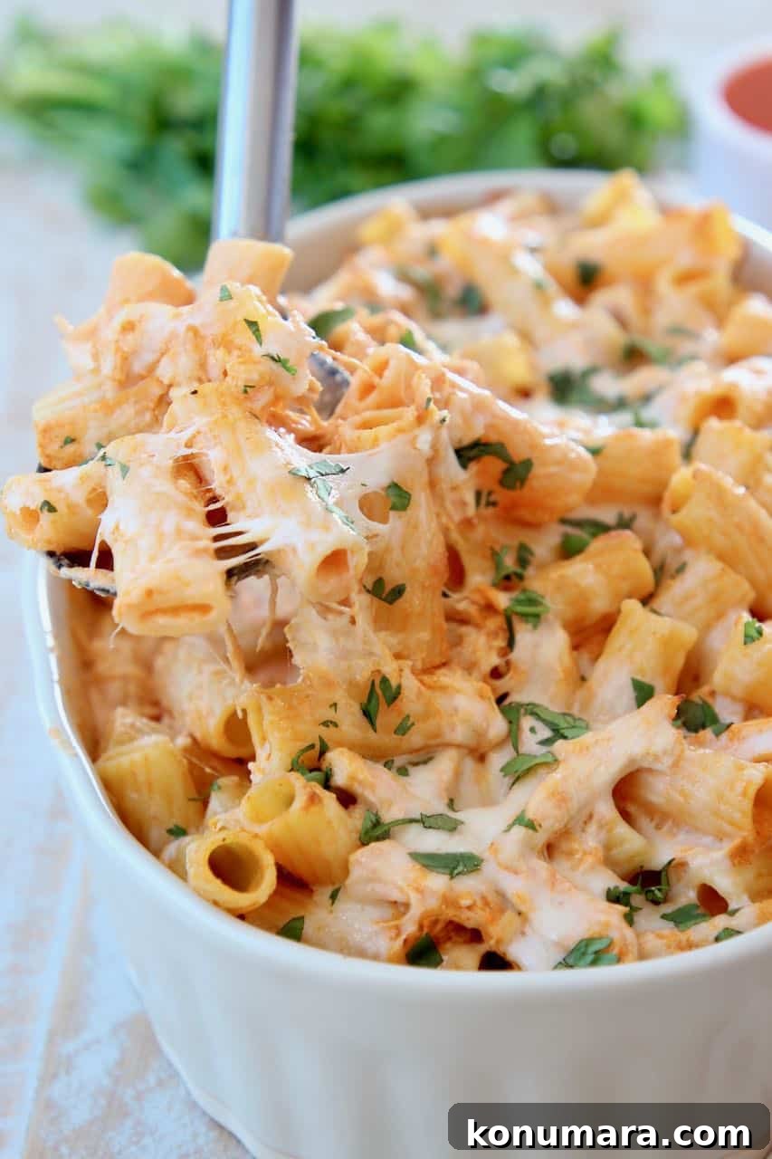 Baked cheesy pasta with spoonful coming out of baking dish