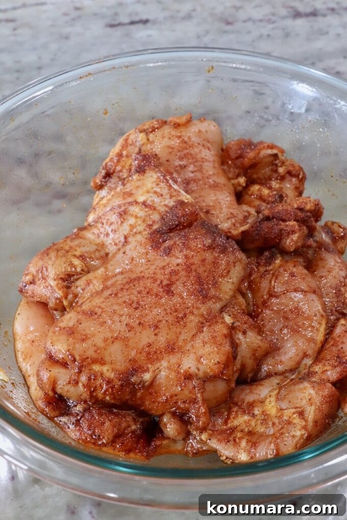 seasoned, raw chicken thighs in a glass bowl