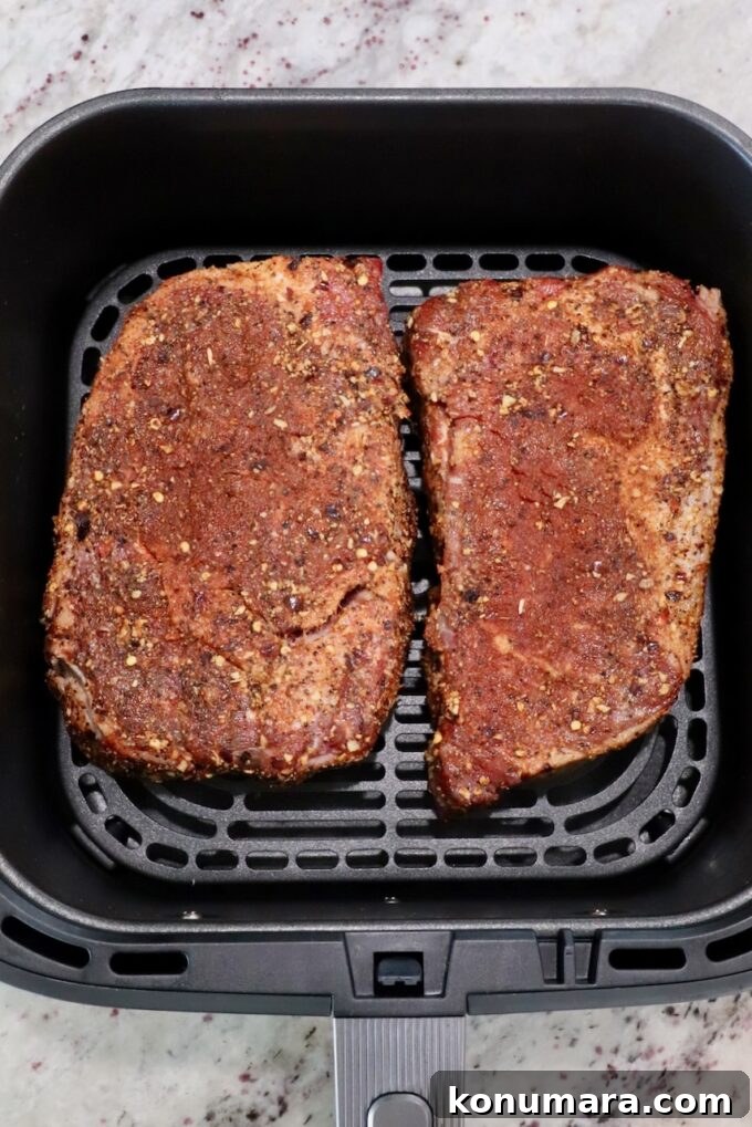seasoned ribeye steaks in an air fryer basket