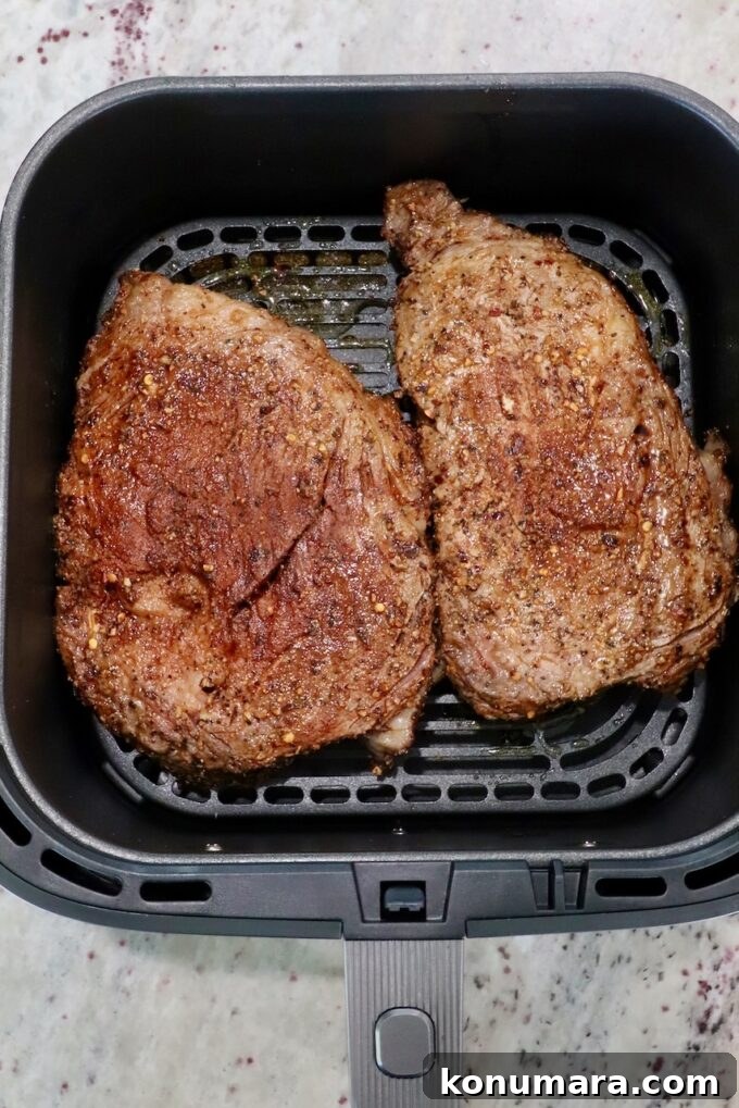 seasoned ribeye steaks in an air fryer basket