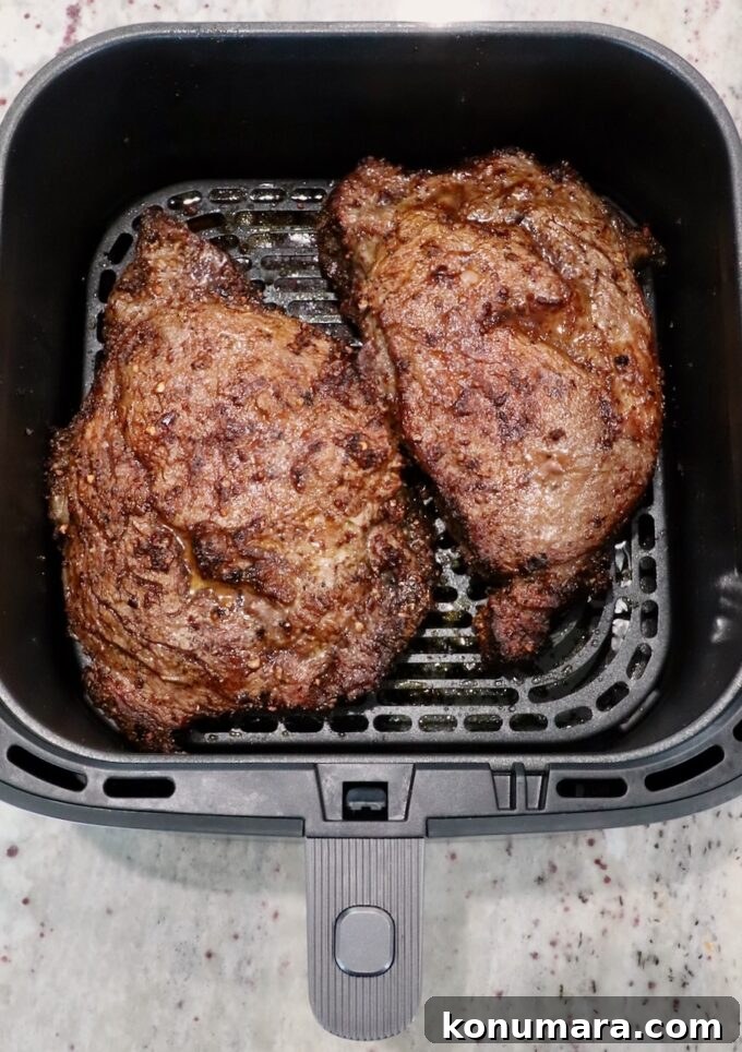 cooked ribeye steaks in an air fryer basket