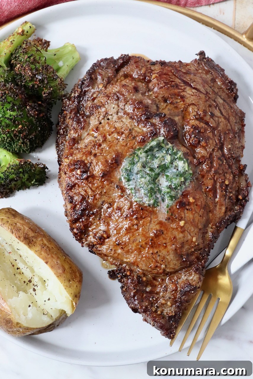 cooked ribeye steak on a plate with a fork, baked potato and cooked broccoli