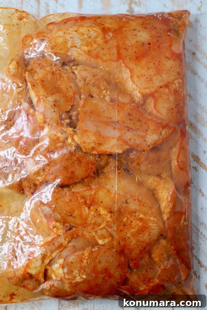 Juicy Grilled Sazon Chicken Thighs Recipe 4 chicken thighs marinating in sazon seasoning in a large plastic bag