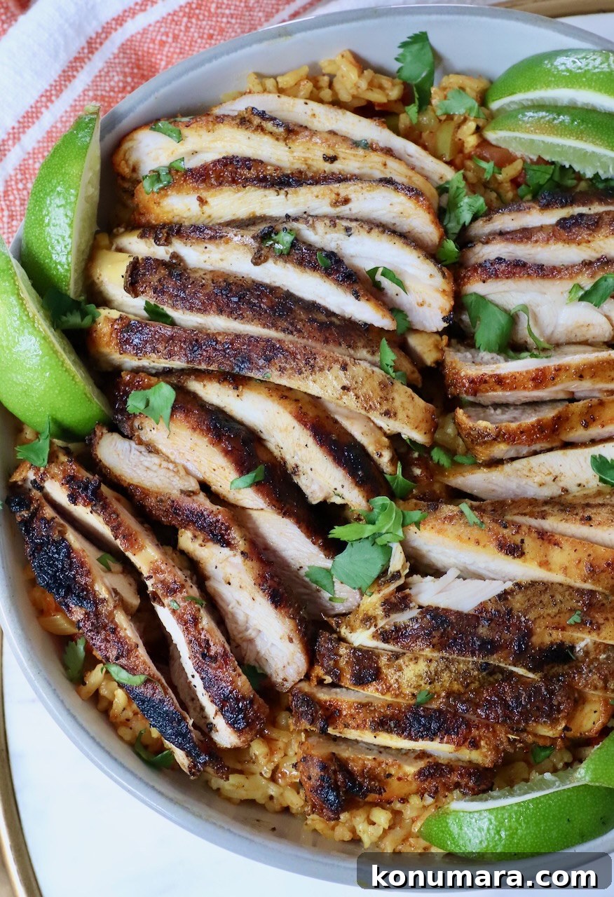 Juicy Grilled Sazon Chicken Thighs Recipe 8 sliced chicken in a bowl with lime wedges on top of yellow rice