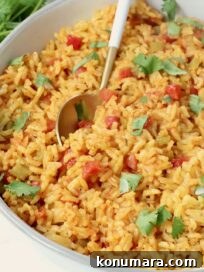 Yellow rice in a bowl with a spoon and fresh cilantro