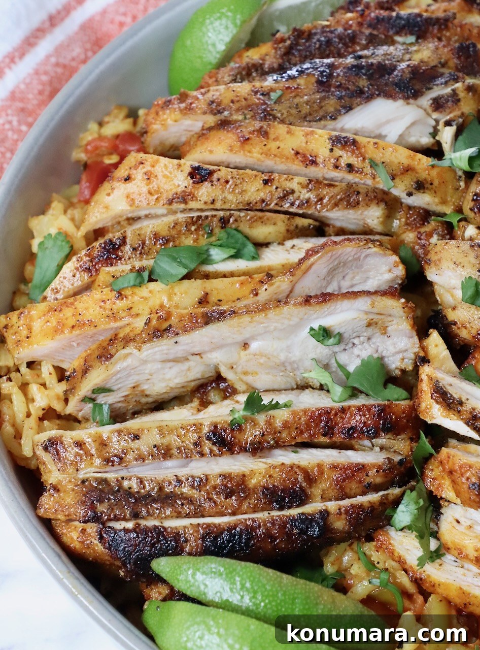 Sliced grilled chicken thighs in a bowl with rice and lime wedges