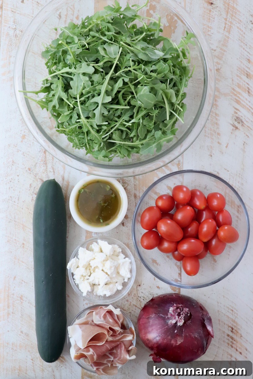Cucumber, Arugula and Prosciutto Salad with Lemon Vinaigrette 3 ingredients for cucumber prosciutto salad on a white wood board