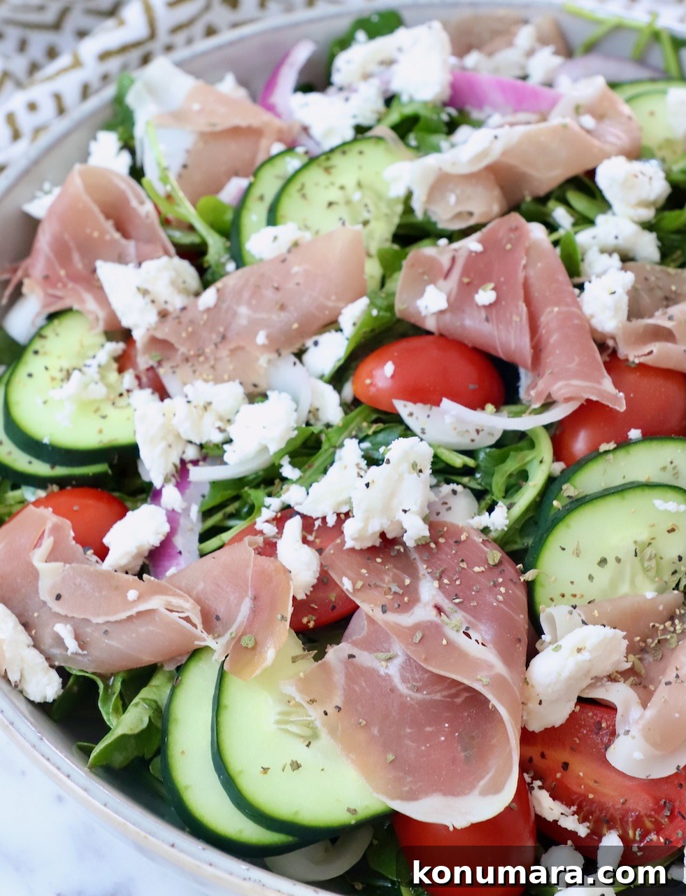 Cucumber, Arugula and Prosciutto Salad with Lemon Vinaigrette 4 prosciutto, cucumber slices and tomatoes on top of a salad in a bowl