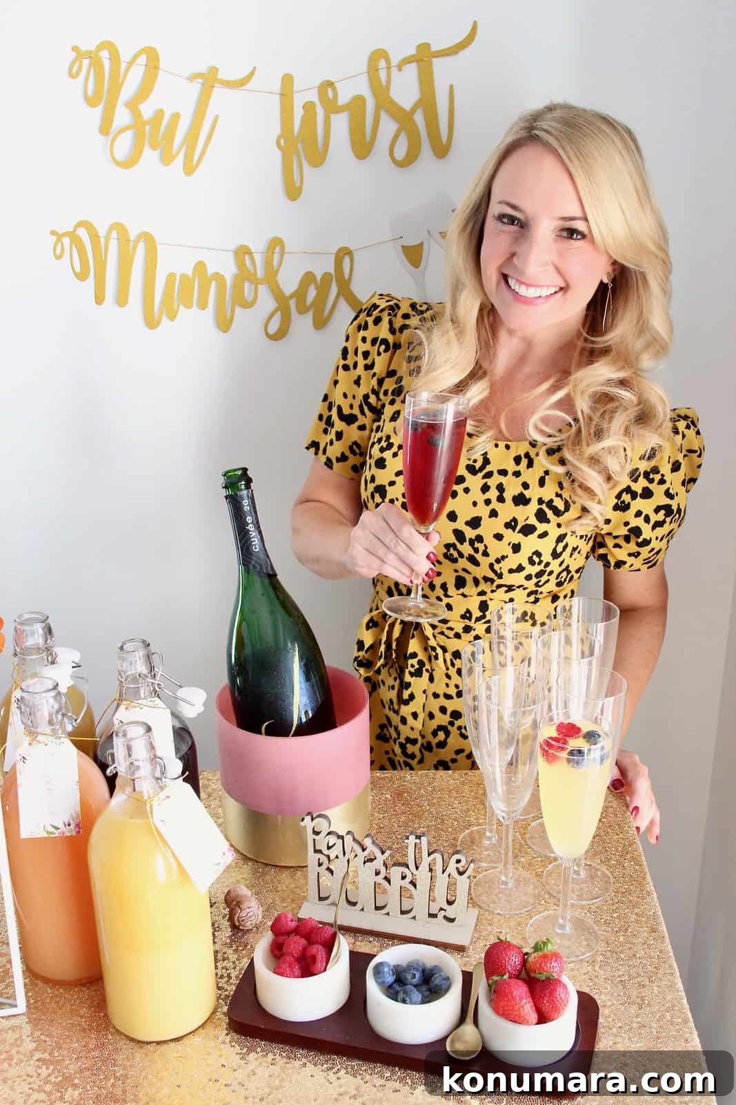 Woman holding mimosa standing behind mimosa bar