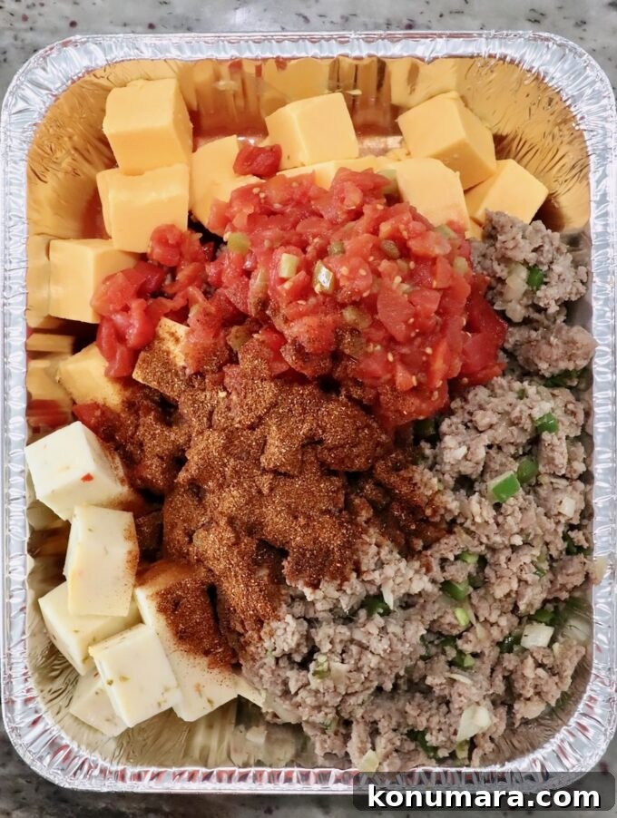 How to Make Smoked Queso Dip 7 Cubes of cheese, cooked, crumbled sausage, diced tomatoes and chili seasoning in an aluminum pan