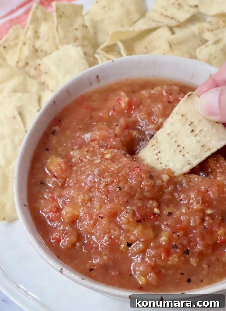 Fresh Peach Salsa with Jalapeño and Cilantro 2 hand dipping a tortilla chip in a bowl of peach salsa