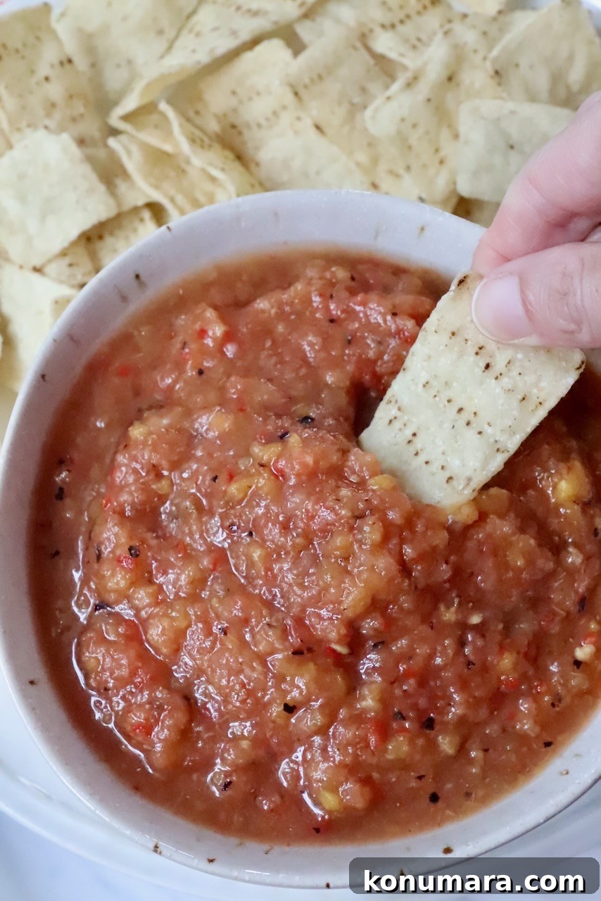 Fresh Peach Salsa with Jalapeño and Cilantro 9 hand dipping a tortilla chip in a bowl of peach salsa
