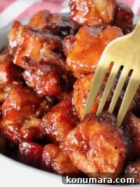 pork belly burnt ends in a bowl with a fork in one piece of pork belly