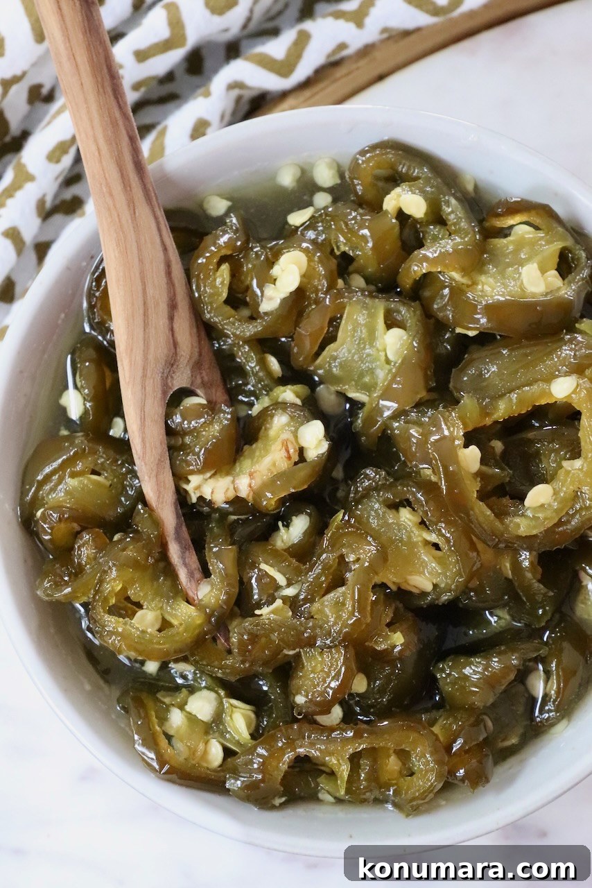 How to Make Sweet and Spicy Candied Jalapenos 2 candied jalapenos in a bowl with a wooden fork