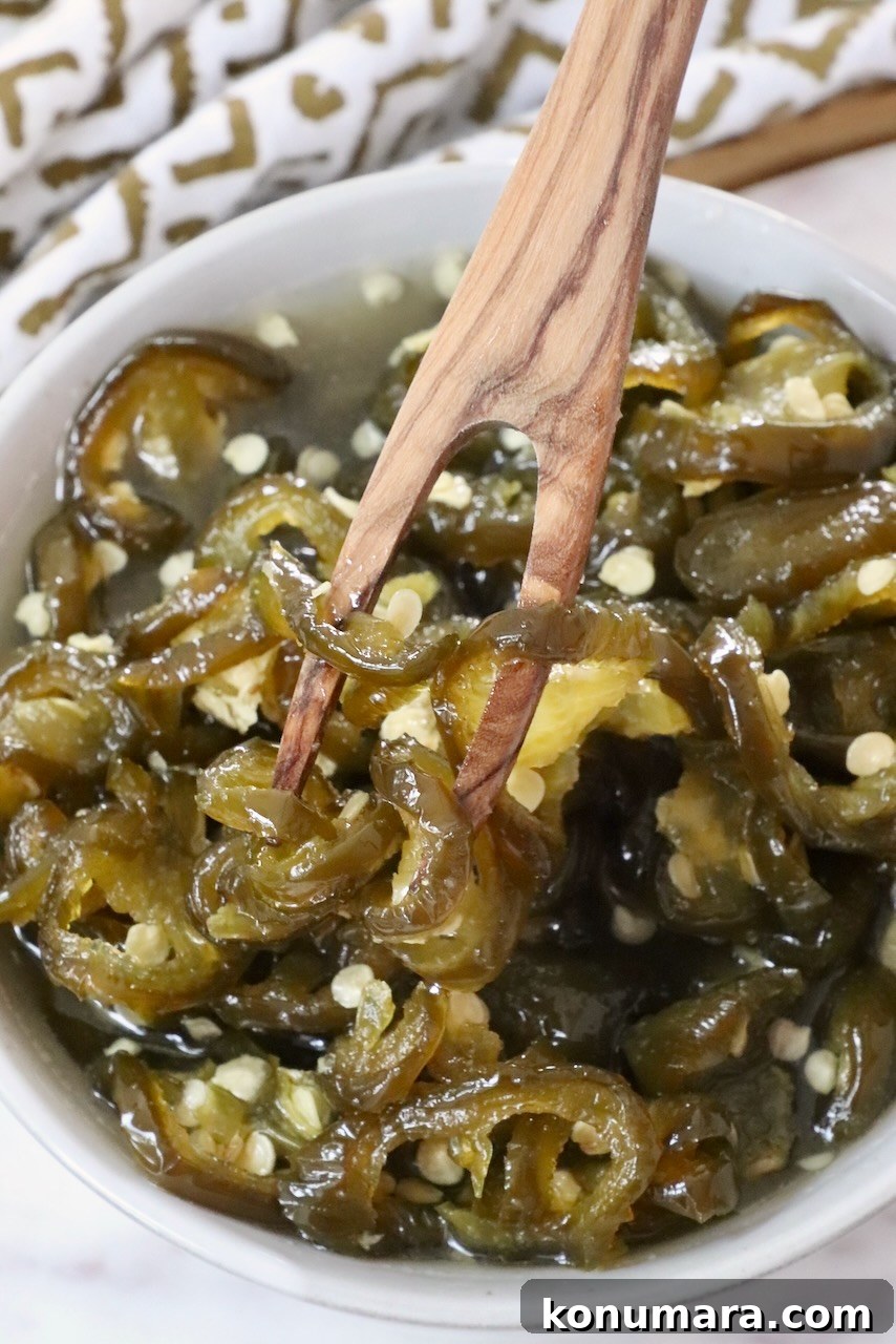 How to Make Sweet and Spicy Candied Jalapenos 8 candied jalapenos in a bowl with a wooden fork