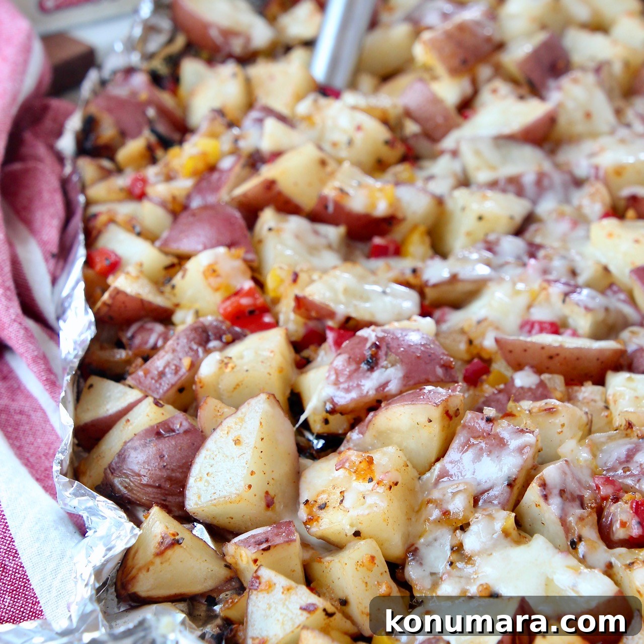 cheesy grilled cubed potatoes in foil with spatula