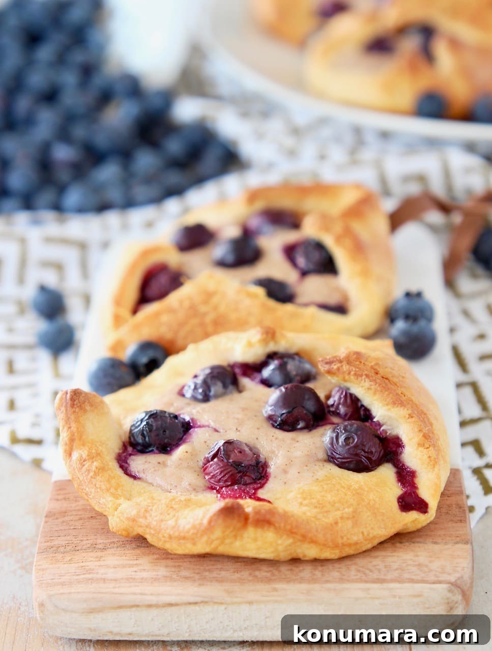 Blueberry Pastry Recipes: Flaky Treats and Baking Tips 2 Blueberry pastry made with crescent roll dough, sitting on wood and marble cutting board with fresh blueberries on the side and behind
