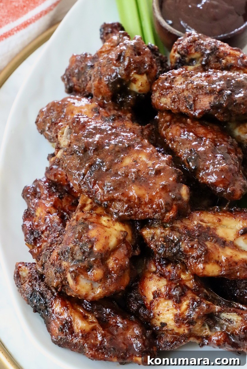 Crispy BBQ Chicken Wings with Tangy Glaze 2 cooked chicken wings tossed in sauce stacked up on a plate