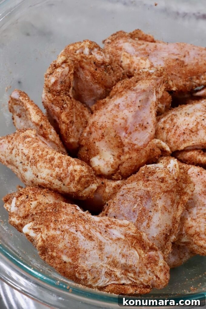 Crispy BBQ Chicken Wings with Tangy Glaze 4 seasoned raw chicken wings in a glass bowl