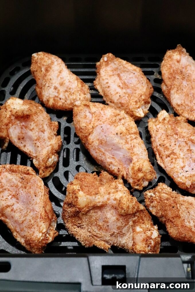 Crispy BBQ Chicken Wings with Tangy Glaze 5 seasoned raw chicken wings in an air fryer basket