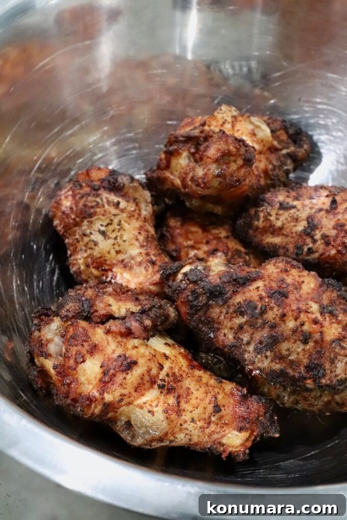 Crispy BBQ Chicken Wings with Tangy Glaze 6 seasoned cooked chicken wings in a metal bowl