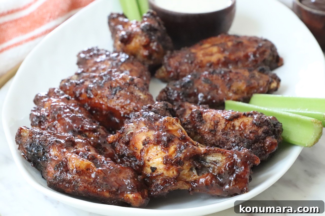 Crispy BBQ Chicken Wings with Tangy Glaze 7 cooked chicken wings tossed in bbq sauce on a plate with celery sticks