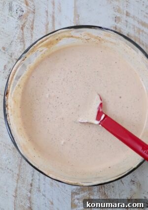 creamy Cajun sauce mixed together in a glass bowl with a red spatula