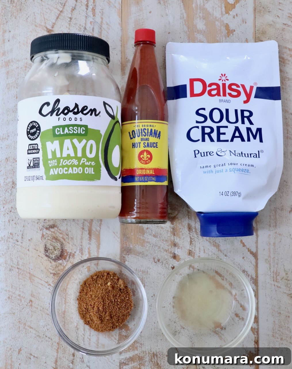 ingredients for creamy cajun sauce on a white wood board