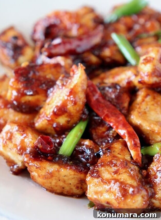 General tso chicken on plate with red chilies and scallions
