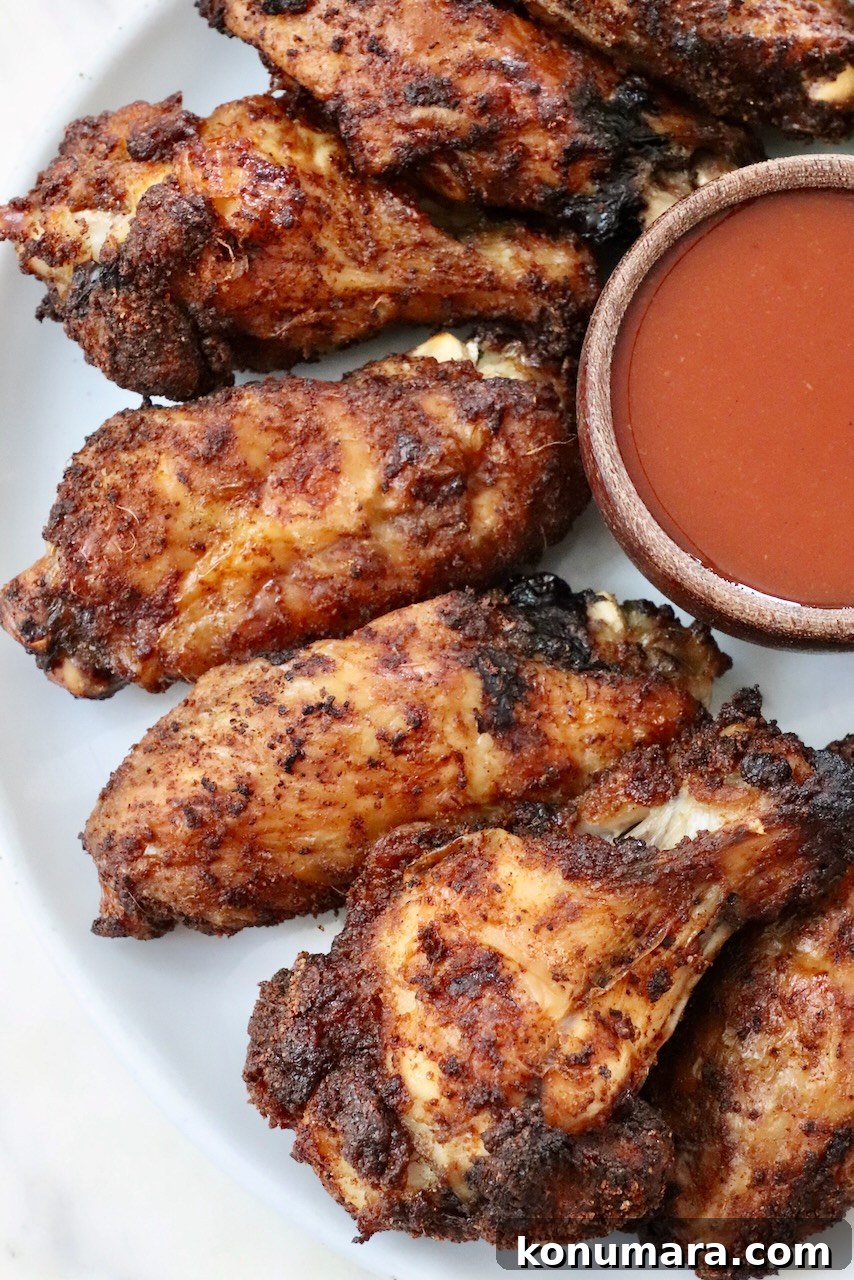 baked chicken wings on a plate with a small bowl of buffalo sauce