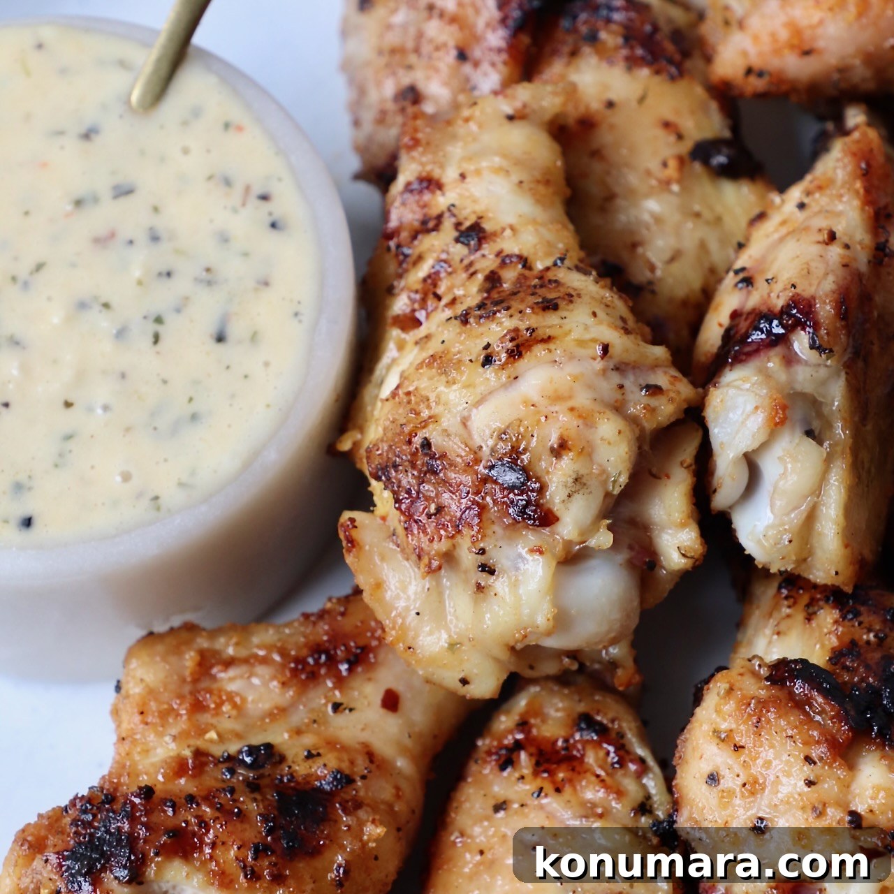 grilled chicken wings on plate with a small bowl of garlic parmesan sauce on the side