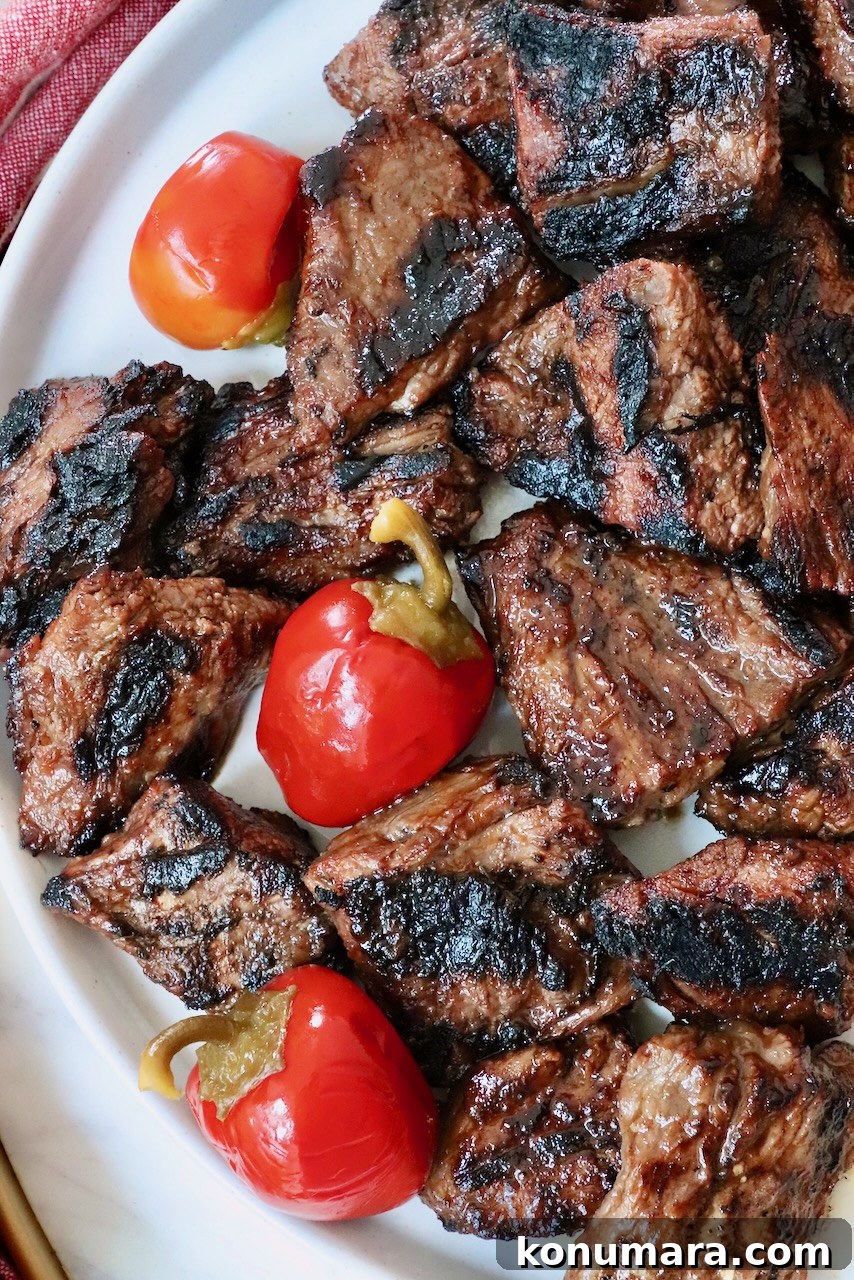 Grilled Steak Tips: Marinade, Sear, and Serve 2 grilled steak tips on a plate with cherry peppers