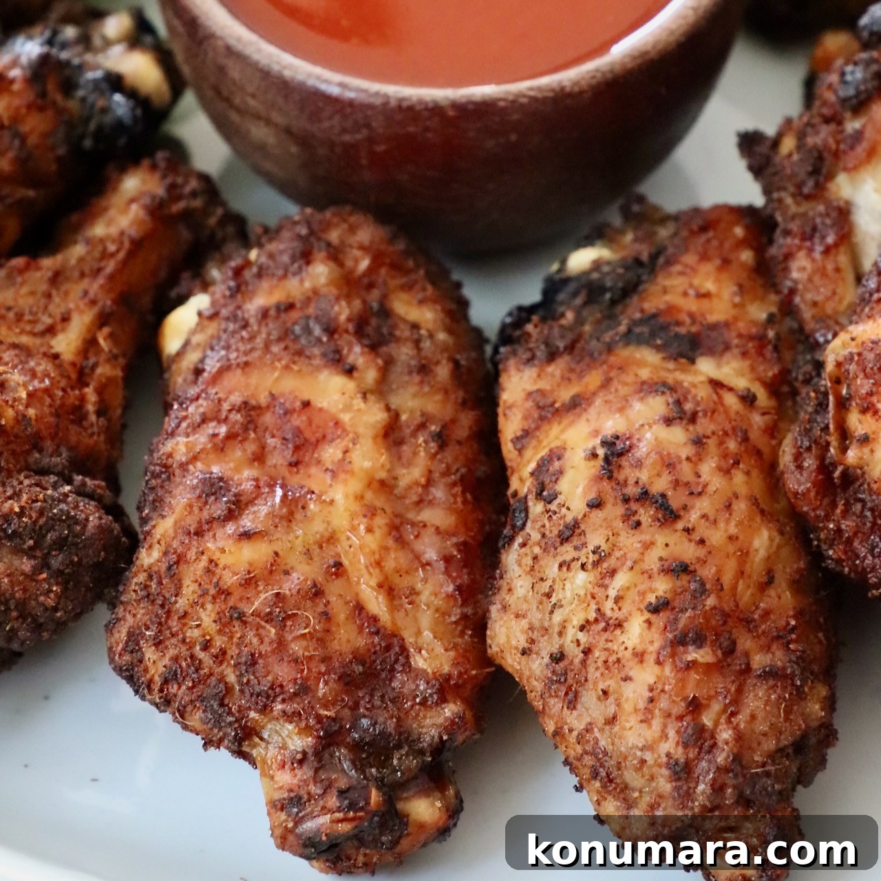 baked chicken wings on a plate with a small bowl of buffalo sauce