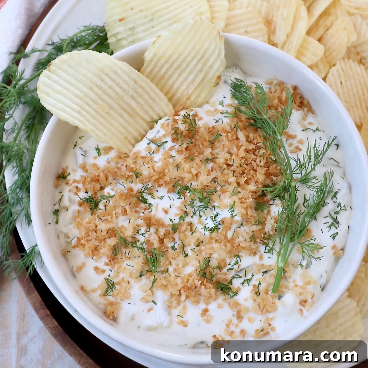 pickle dip in bowl topped with toasted breadcrumbs, with chips in the dip