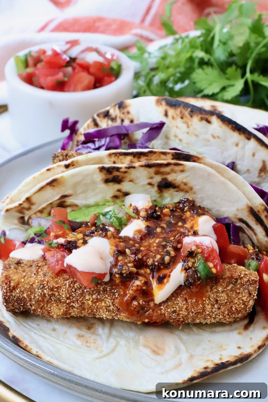 fish taco with crispy breading, topped with vibrant salsa, creamy sauce, and shredded red cabbage, set against fresh cilantro and a small salsa dish.