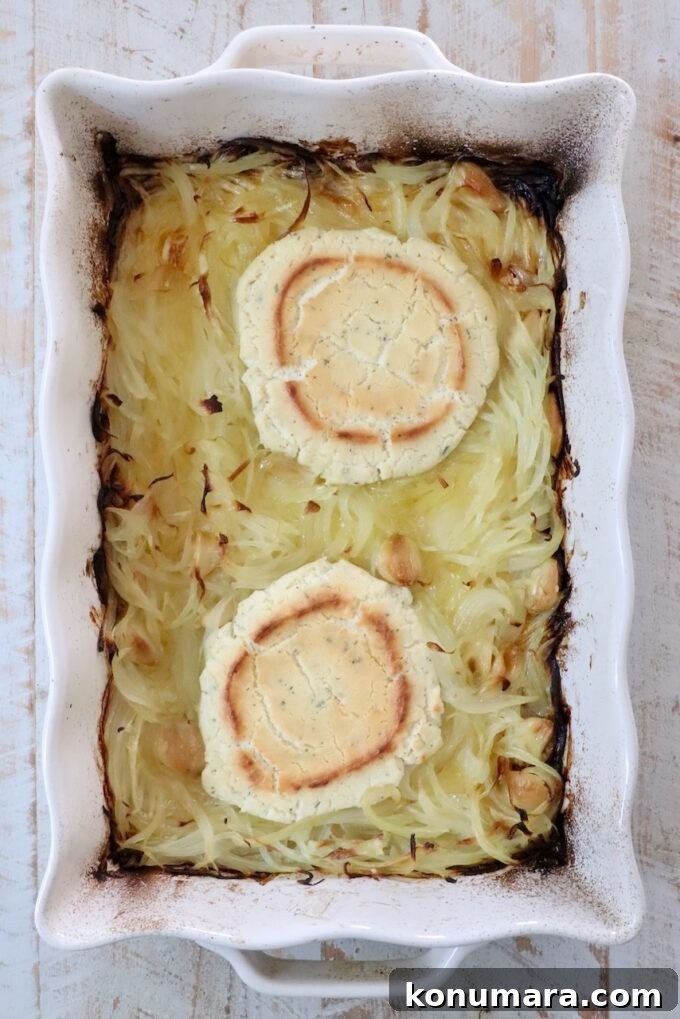 baked rounds of boursin cheese and caramelized onions in a white casserole dish