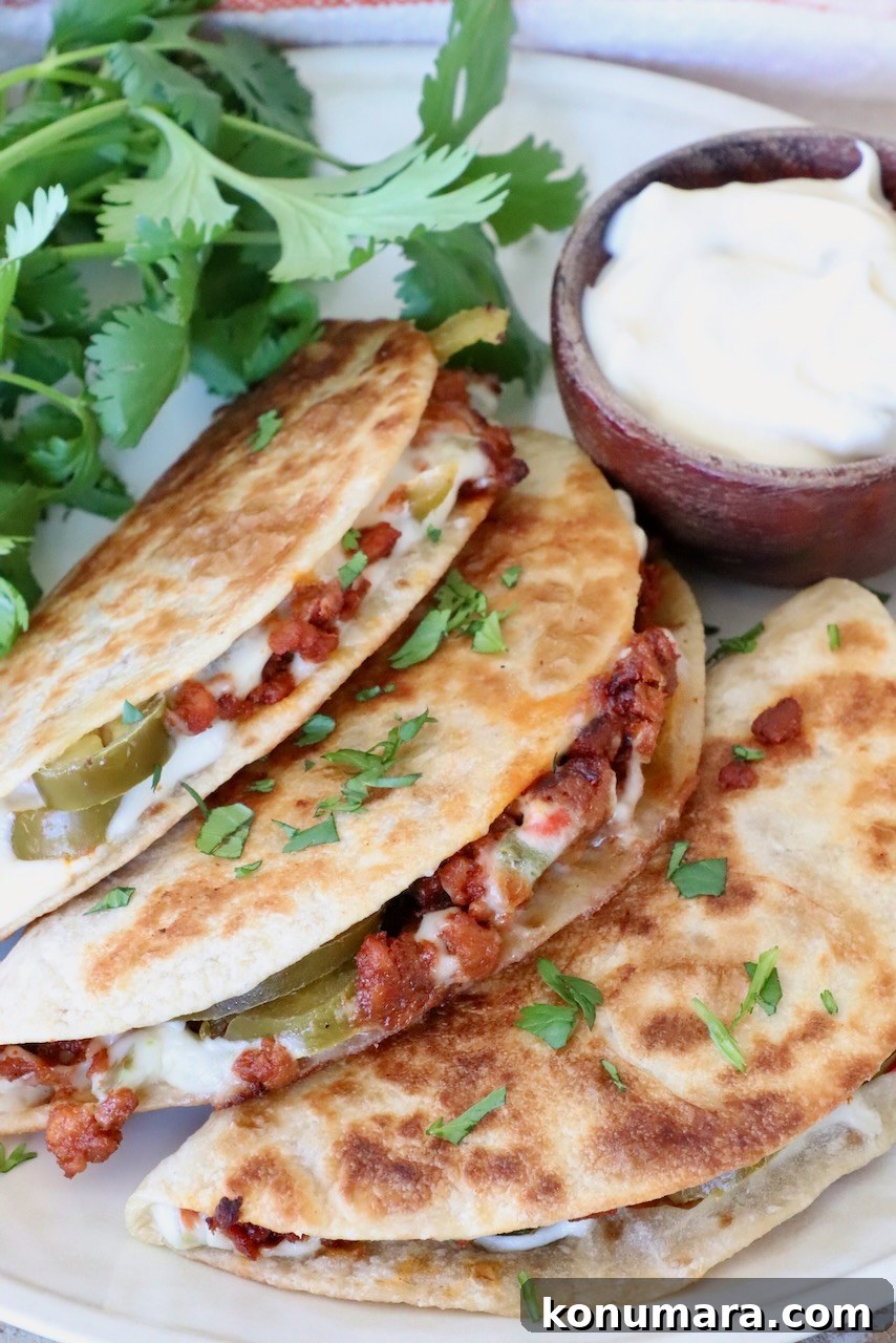 Crispy Chorizo Tacos with Melted Queso 2 Three crispy tacos filled with meat, cheese, and jalapeños are garnished with cilantro. A small bowl of white queso sits beside them.