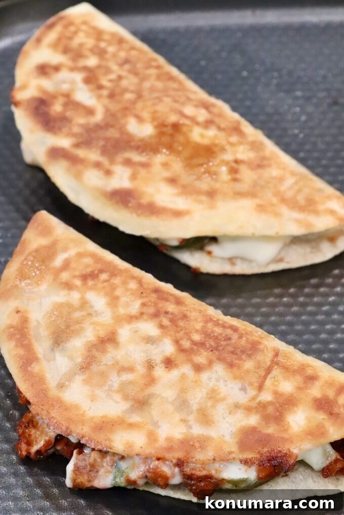 Crispy Chorizo Tacos with Melted Queso 9 Two golden-brown crispy tacos sit in a pan, filled with melted cheese and chorizo.
