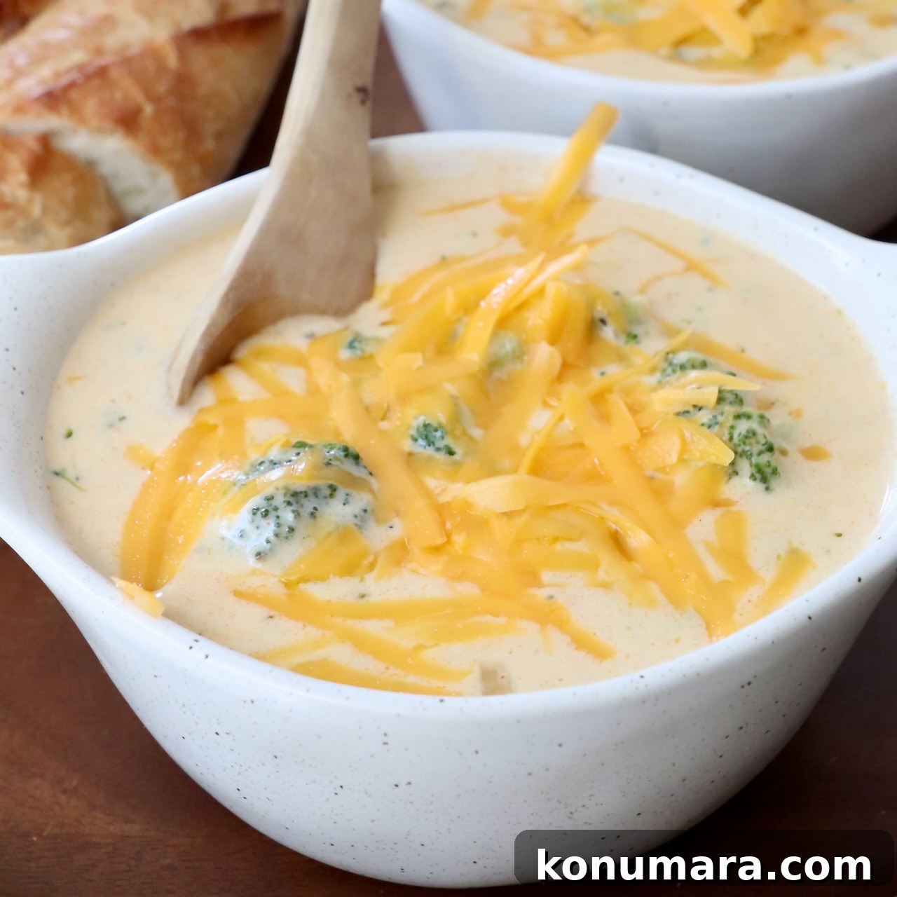 37 Cozy Fall Soup Recipes to Warm the Soul 5 broccoli cheddar soup in bowl topped with shredded cheddar cheese with wooden spoon in the bowl
