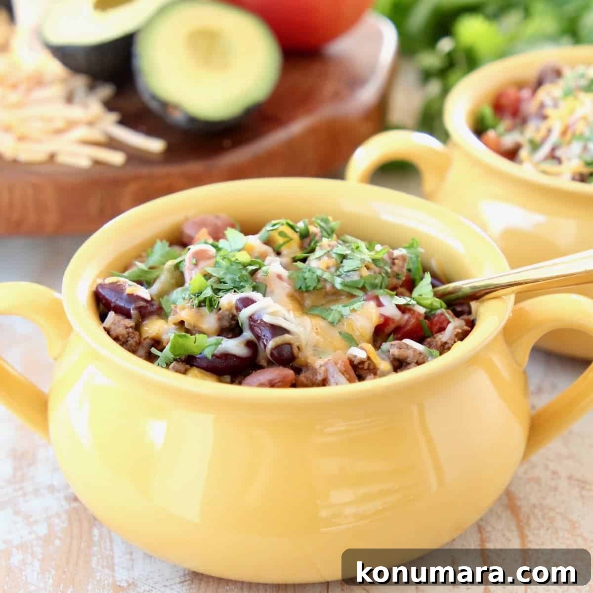 37 Cozy Fall Soup Recipes to Warm the Soul 10 Crockpot Taco Soup in yellow crock with gold spoon, topped with cheddar cheese and fresh cilantro