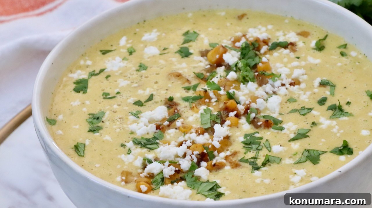 Mexican Street Corn Soup Recipe (Elote-Inspired) 9 A creamy soup topped with crumbled cheese, cilantro, and golden corn kernels fills a white bowl.