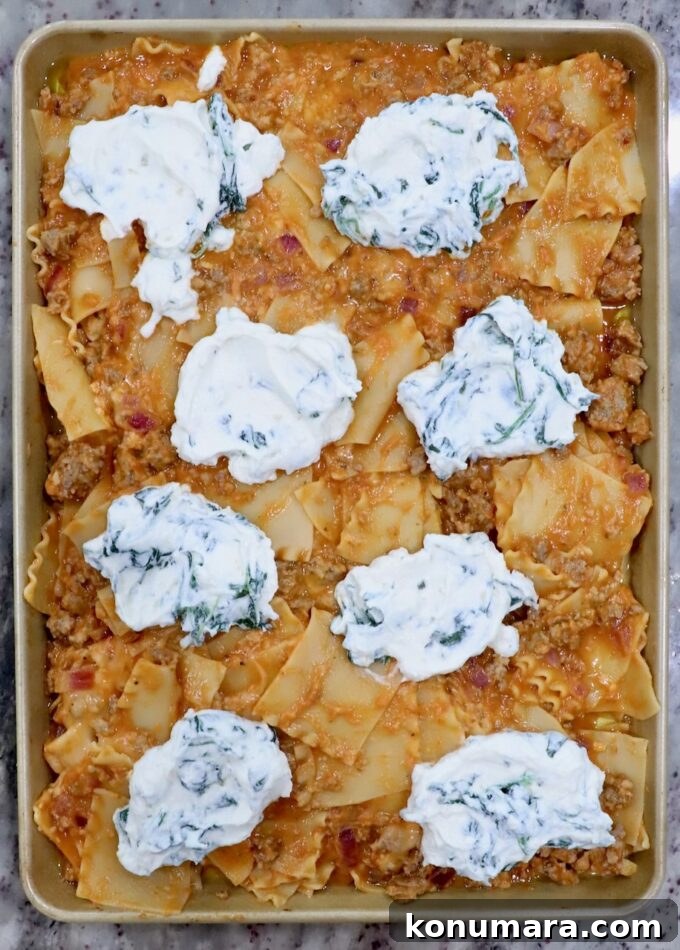 Sheet-Pan Butternut Squash Lasagna Recipe 9 uncooked lasagna on a sheet pan topped with large dollops of spinach ricotta cheese