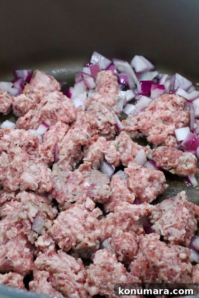 Sheet-Pan Butternut Squash Lasagna Recipe 6 raw crumbled sausage in a pan with diced onions