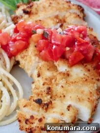 crispy chicken sliced on a plate topped with tomato bruschetta with creamy pasta noodles on the side