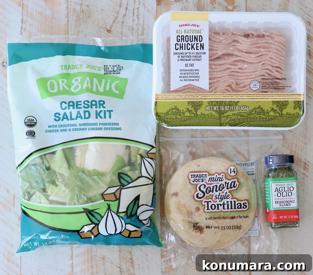 Trader Joe’s products on a wooden surface: organic Caesar salad kit, ground chicken, mini Sonora tortillas, and Aglio Olio seasoning blend.