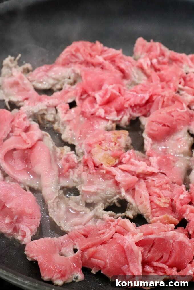 partially cooked thinly sliced steak in a skillet